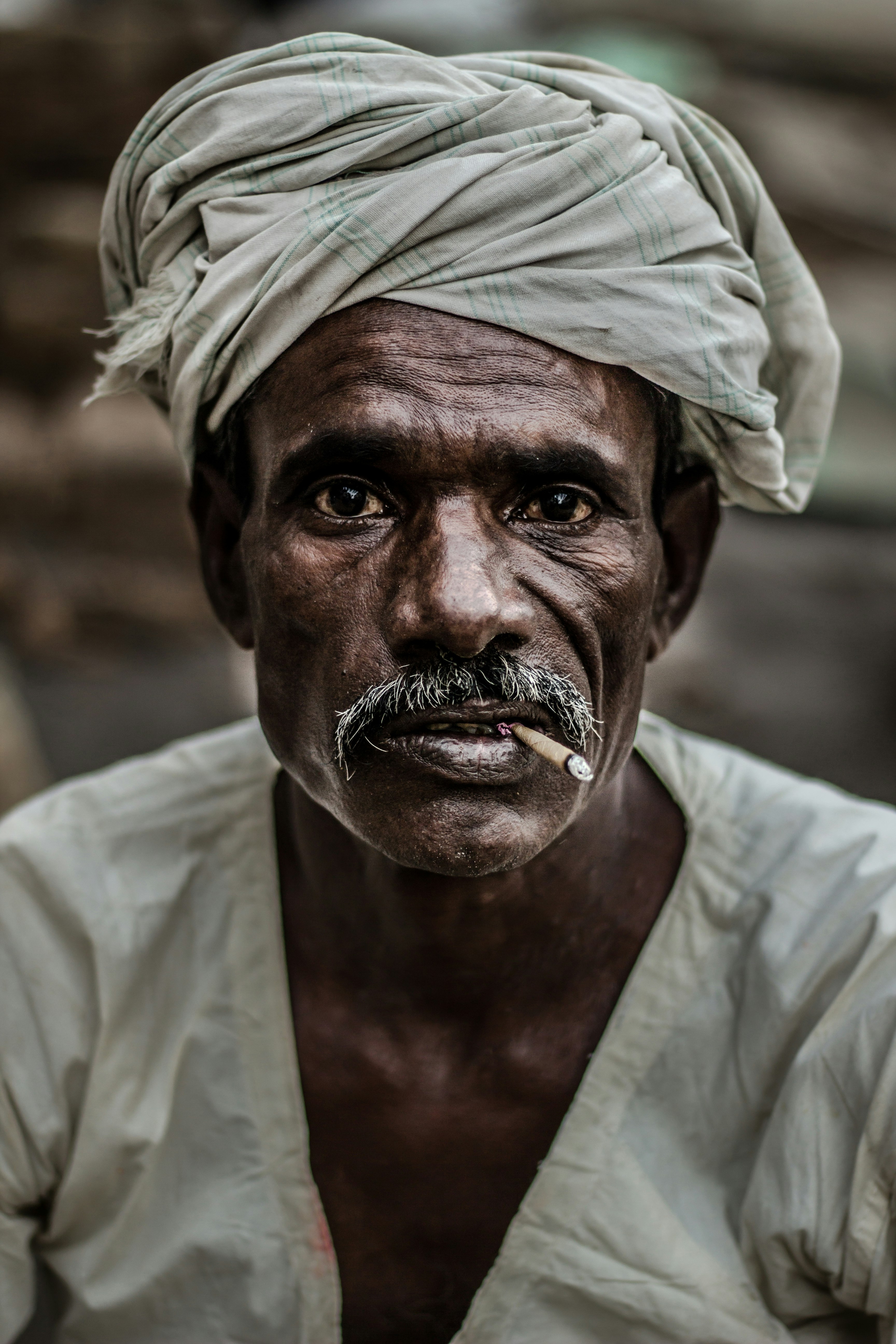 man wearing gray turban smoking cigarette in closeup photography